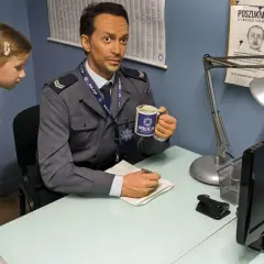 W muzeum Ojca Mateusza dziewczynka przygląda się figurze policjanta z kubkiem "POLICJA".