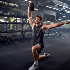 Mężczyzna w siłowni wykonuje ćwiczenie z kettlebell. To tbc co to za ćwiczenie, ale wygląda na skuteczne.
