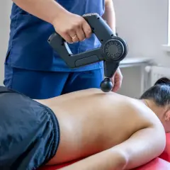 Fizjoterapeuta wykonuje masaż wibracyjny pleców. Choć zazwyczaj przynosi ulgę, warto pamiętać o potencjalnych masaż wibracyjny skutki uboczne.