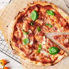 En nybakad pizza med tomatsås, ost och basilika. En bit är bortskuren, perfekt för att njuta av goda pizza kalorier.