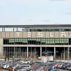 Tesla-Fabrik mit vielen Autos auf dem Parkplatz. Der Tesla-Betriebsrat vertritt die Interessen der Belegschaft.