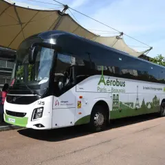 L'Aérobus Paris-Beauvais, un bus blanc et vert orné de monuments parisiens, attend des passagers sous une structure de toit.