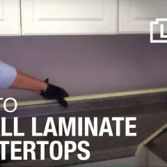 Learn how to install laminate countertops with this helpful guide. A person in gloves is shown working on a countertop.