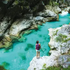Wanderin am Juliana Trail: Eine Frau mit Rucksack steht auf einem Felsen und blickt auf das türkisfarbene Wasser einer Schlucht.