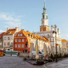 Kolorowe kamienice na Starym Rynku w Poznaniu, gdzie czeka na Ciebie poznań miasto doznań. Ratusz góruje nad placem pełnym ogródków kawiarnianych.
