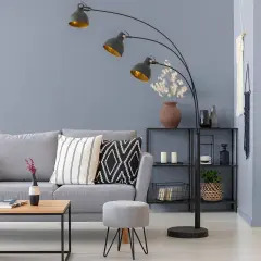 Nowoczesny salon z szarymi ścianami, wygodną sofą i designerską lampą łukową.