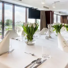 Elegancko nakryty stół z białymi tulipanami, idealny na uroczystość. Zastanawiasz się, ile trwa komunia w restauracji? To zależy od wielu czynników, ale zazwyczaj trwa kilka godzin.
