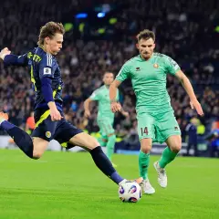 Piłkarz w granatowym stroju strzela do bramki, podczas gdy zawodnik w zielonym stroju z numerem 14 próbuje go zatrzymać. Mecz Francja Dania.