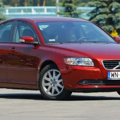 Czerwone Volvo S40 II z polskimi tablicami rejestracyjnymi WN 94827 zaparkowane na zewnątrz.