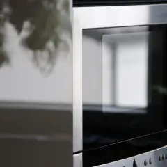 Elegancki, metalowy front nowoczesnej kuchenki mikrofalowej z widocznym panelem sterowania i wyświetlaczem.