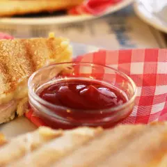 Un sándwich a la parrilla con una pequeña taza de ketchup. ¿El ketchup es dulce o salado?