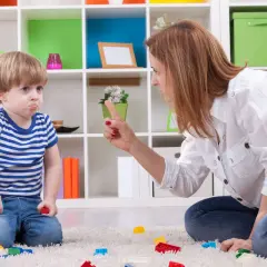 Niño con cara de enfado, actitud negativista desafiante, mientras su madre le regaña.