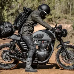 Motociclista con zaino e borse moto custom, pronto per un'avventura su sterrato.