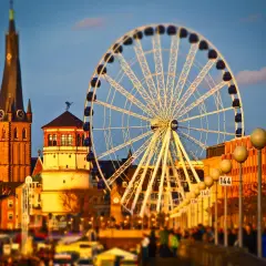 Zachód słońca nad Renem, gdzie dusseldorf atrakcje, takie jak diabelski młyn i wieża kościelna, tworzą malowniczy krajobraz.