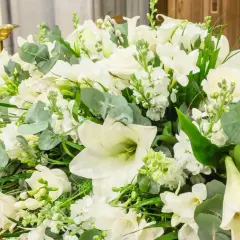 Białe lilie i inne kwiaty tworzą elegancki bukiet, idealny jako wyraz pamięci i szacunku.