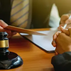 Sądowy młotek i dłonie w geście proszenia o pomoc. Rozmowa o kredycie, być może o sankcji kredytu darmowego.