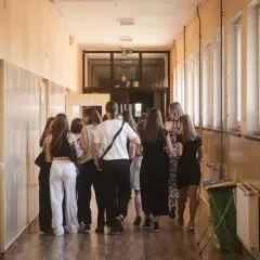 Grupa uczniów w szkolnym korytarzu, nerwowo oczekująca na rozpoczęcie egzaminów ósmoklasisty.