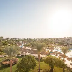 Słoneczny dzień w kurorcie Long Beach Resort Hurghada. Palmy, baseny i leżaki pod strzechą zapraszają do relaksu.