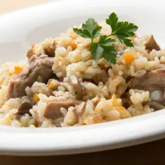 Delicioso arroz con champiñones y trozos de carne, adornado con perejil fresco.