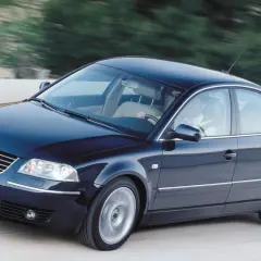 Ciemnoniebieski Passat W8 z jasnym wnętrzem pędzi po drodze, za kierownicą siedzi mężczyzna.