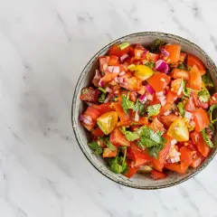 En skål med färsk pico de gallo, full av tärnad tomat, rödlök och koriander. Perfekt till tacosen!