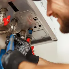 Tecnico con guanti lavora su una caldaia. Speriamo che la caldaia parte da sola dopo la sua riparazione.