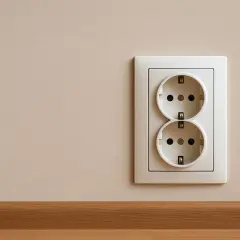 Białe podwójne gniazdko elektryczne na jasnej ścianie, zamontowane na standardowej wysokości.