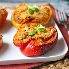 Pimientos rellenos vegetarianos, dorados y gratinados, con una hoja de albahaca fresca coronando cada uno.