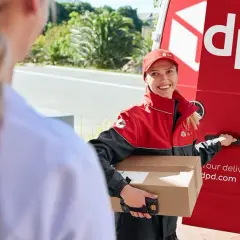 Kurierka DPD z uśmiechem przekazuje przesyłkę do doręczenia w punkcie pickup.