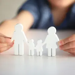Dziecko z autyzmem delikatnie dotyka drewnianych figurek symbolizujących rodzinę, tworząc więź.
