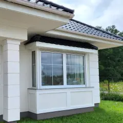 Frisch gestrichene weiße Fassade mit Fenster und Säulen.