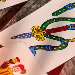 Carte da gioco napoletane, tra cui il sette di spade e un personaggio. Immagina come si gioca a cucù con queste carte!