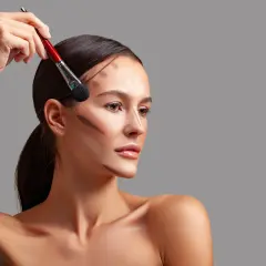 Modelka z pociągnięciami bronzera na twarzy, pokazującymi, do czego służy bronzer: podkreślenia rysów i nadania głębi.
