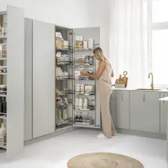 Kobieta wybiera produkty z wysokiej szafy z systemem szuflad, idealnej do przechowywania pokrywek i przetworów.