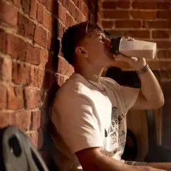 Junger Mann trinkt aus Shaker, bereit für die Kreatin Aufladephase.
