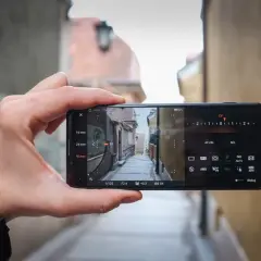 Dłoń trzyma smartfon Sony Xperia Pro, kadrując wąską uliczkę. Widoczne ustawienia aparatu: 50 mm, 1/125, F2.4, ISO 64.