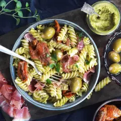 Pasta salad with pesto, sun-dried tomatoes, olives, and prosciutto.