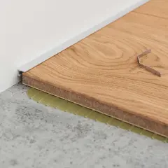 Moderne Alternative zu Sockelleisten: Ein schmales Metallprofil schließt den Boden zur Wand ab. Werkzeug liegt bereit.