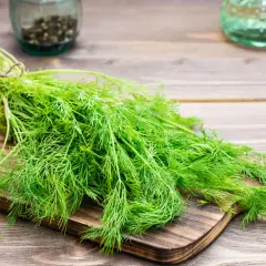 Un manojo de eneldo fresco sobre una tabla de cortar. El eneldo para que sirve es muy versátil en la cocina, aportando sabor a pescados y ensaladas.