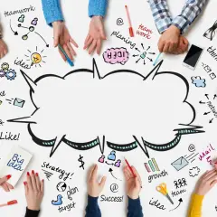 Ludzie tworzą burzę mózgu, rysując na stole schematy: teamwork, idea, plan, vision, share, growth, success.