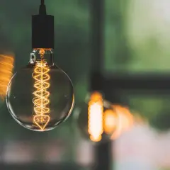 Żarówka z widocznym żarnikiem, jak w modelu pge g12, w ciepłym świetle.