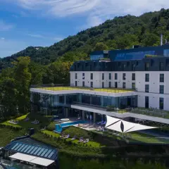 Nowoczesny hotel nad jeziorem Rożnowskim, z basenem i tarasami, otoczony zielenią.