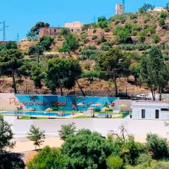 Piscina municipal en el oeste de Almería, rodeada de vegetación y colinas. Un oasis refrescante bajo el sol andaluz.