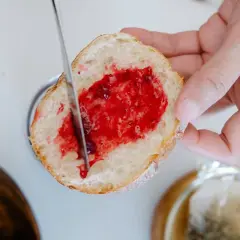 Ein Stück Brot wird mit Marmelade bestrichen, ein Genuss, der die Bedeutung eines Cheat Days unterstreicht.