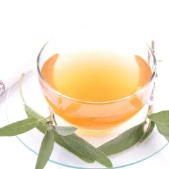 Ein Glas Salbei Tee, der zu lange ziehen gelassen wurde, mit frischen Salbeiblättern und einem gestreiften Tuch.
