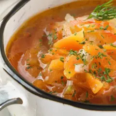 Aksamitna zupa na odchudzanie z kawałkami pomidorów, marchewki i ziemniaków, posypana świeżym szczypiorkiem.