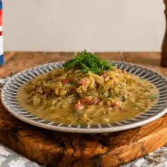 Młoda kapusta duszona z boczkiem i koperkiem, podana na talerzu z szarym wzorem.