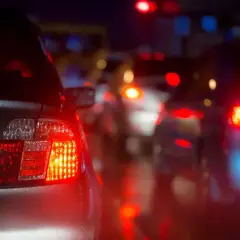 Czerwone światła stopu, czyli "brems licht co to znaczy", oznaczają hamowanie. Samochody stoją w korku nocą, ich światła odbijają się na mokrej drodze.
