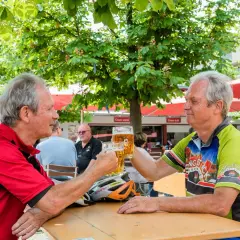 Zwei Radfahrer stoßen im Stadtbiergarten Schorndorf mit Bier an.