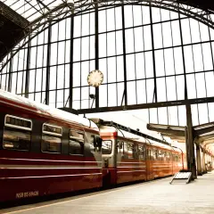 Czerwone pociągi na dworcu pod szklanym dachem. Zastanawiasz się, ile kosztuje pociąg do Berlina?
